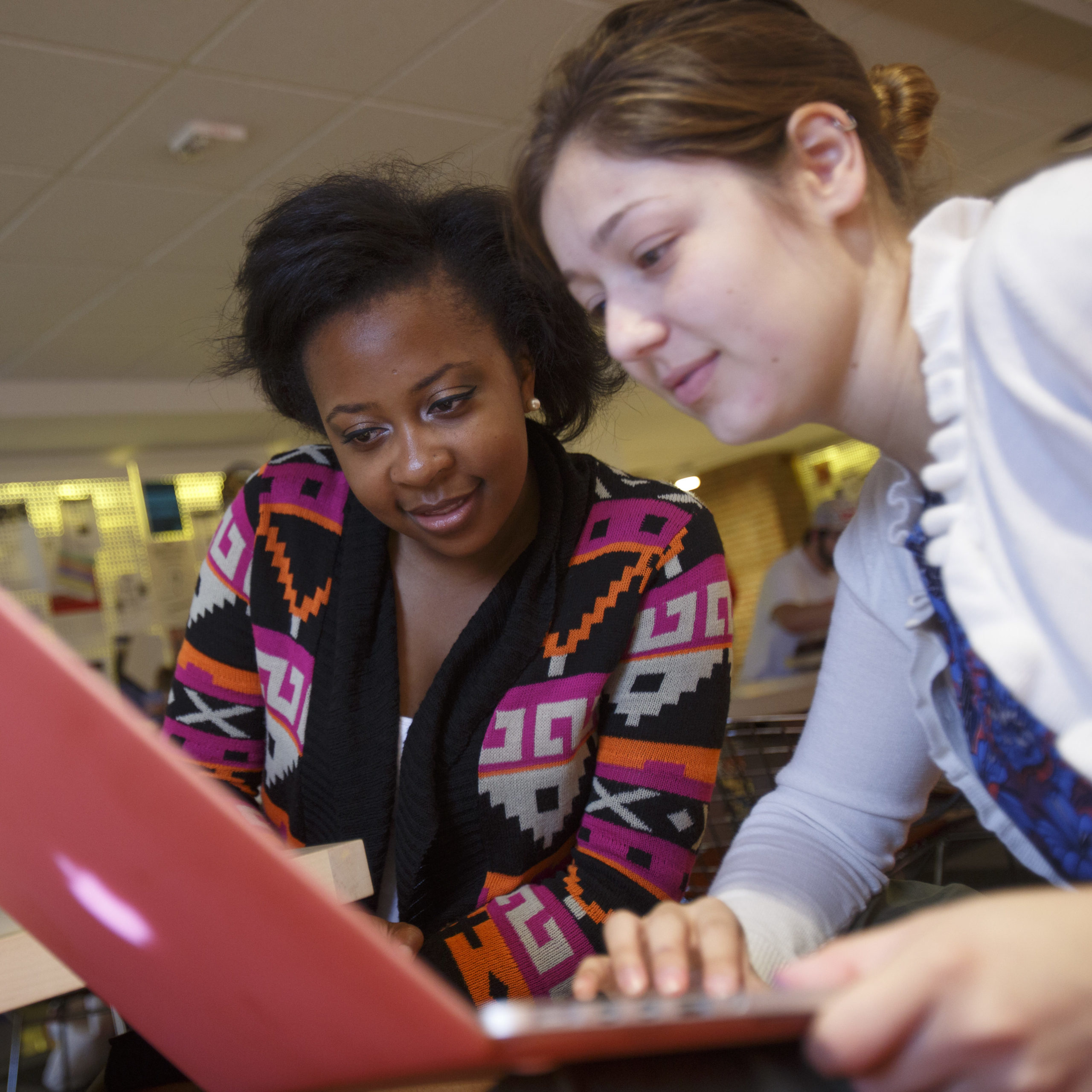 Two female students working together on a laptop. 
